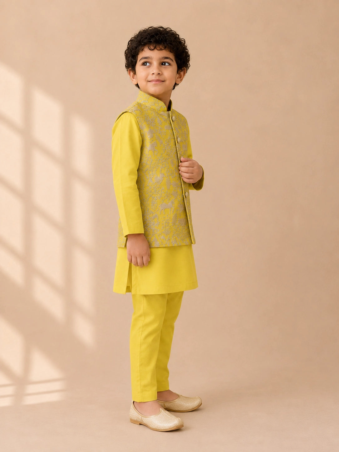 Young boy wearing a bright yellow kurta pajama set with an embroidered waistcoat.