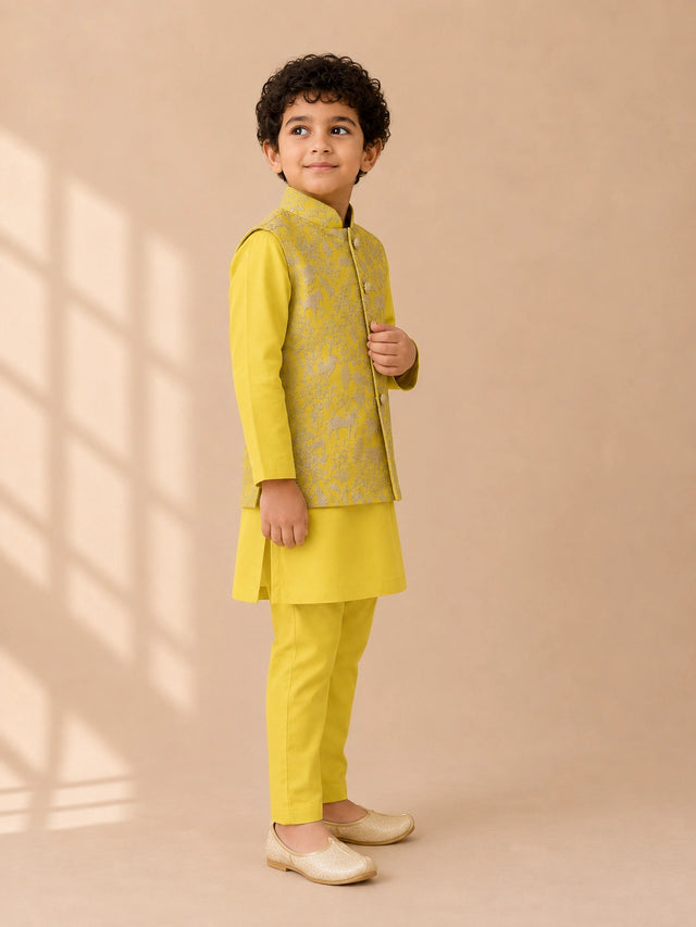 Young boy wearing a bright yellow kurta pajama set with an embroidered waistcoat.
