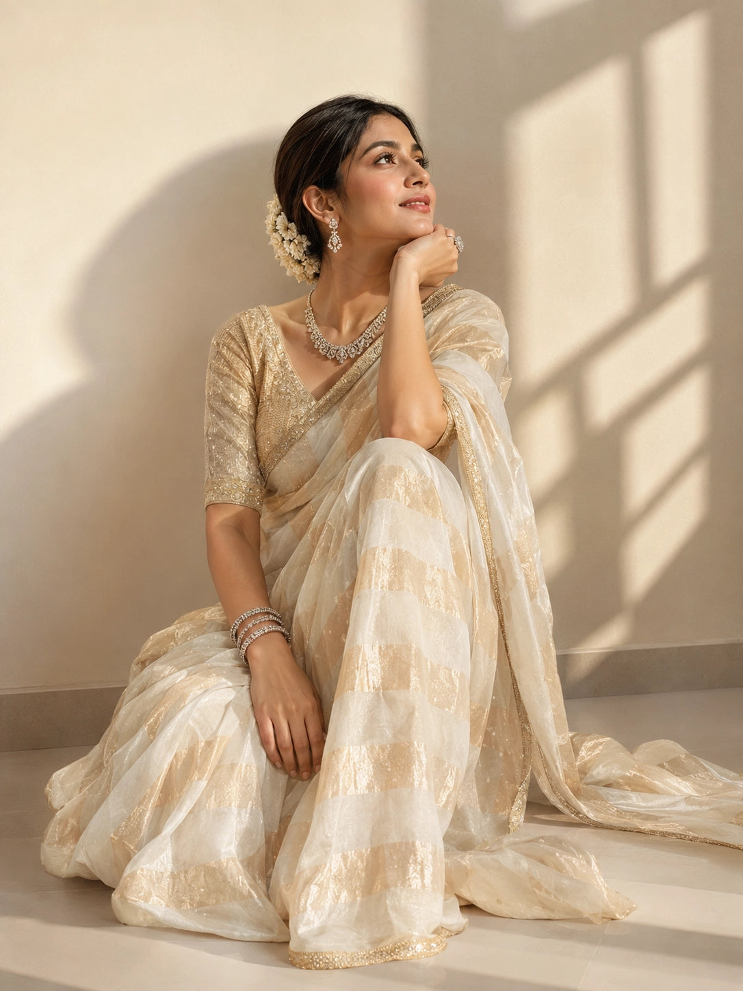 Woman in a cream and gold striped saree with an embroidered blouse.