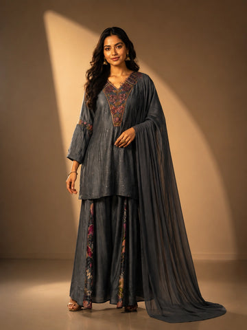 Woman wearing an elegant grey embroidered kurti set with sharara pants and dupatta.