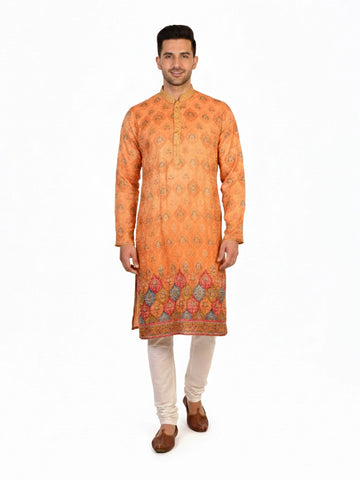 Man wearing an orange embroidered Kurta Pajama with cream pants and brown shoes, showcasing intricate patterns.