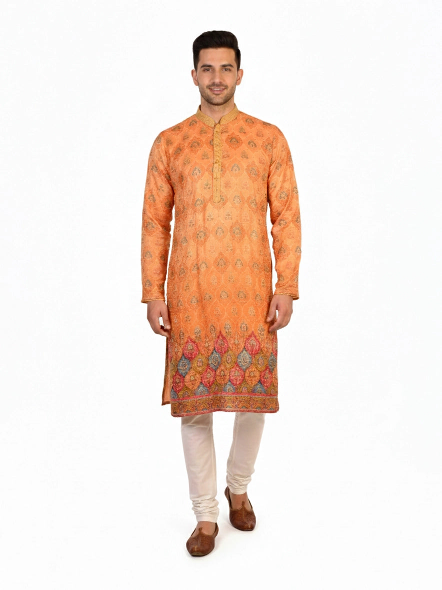 Man wearing an orange embroidered Kurta Pajama with cream pants and brown shoes, showcasing intricate patterns.
