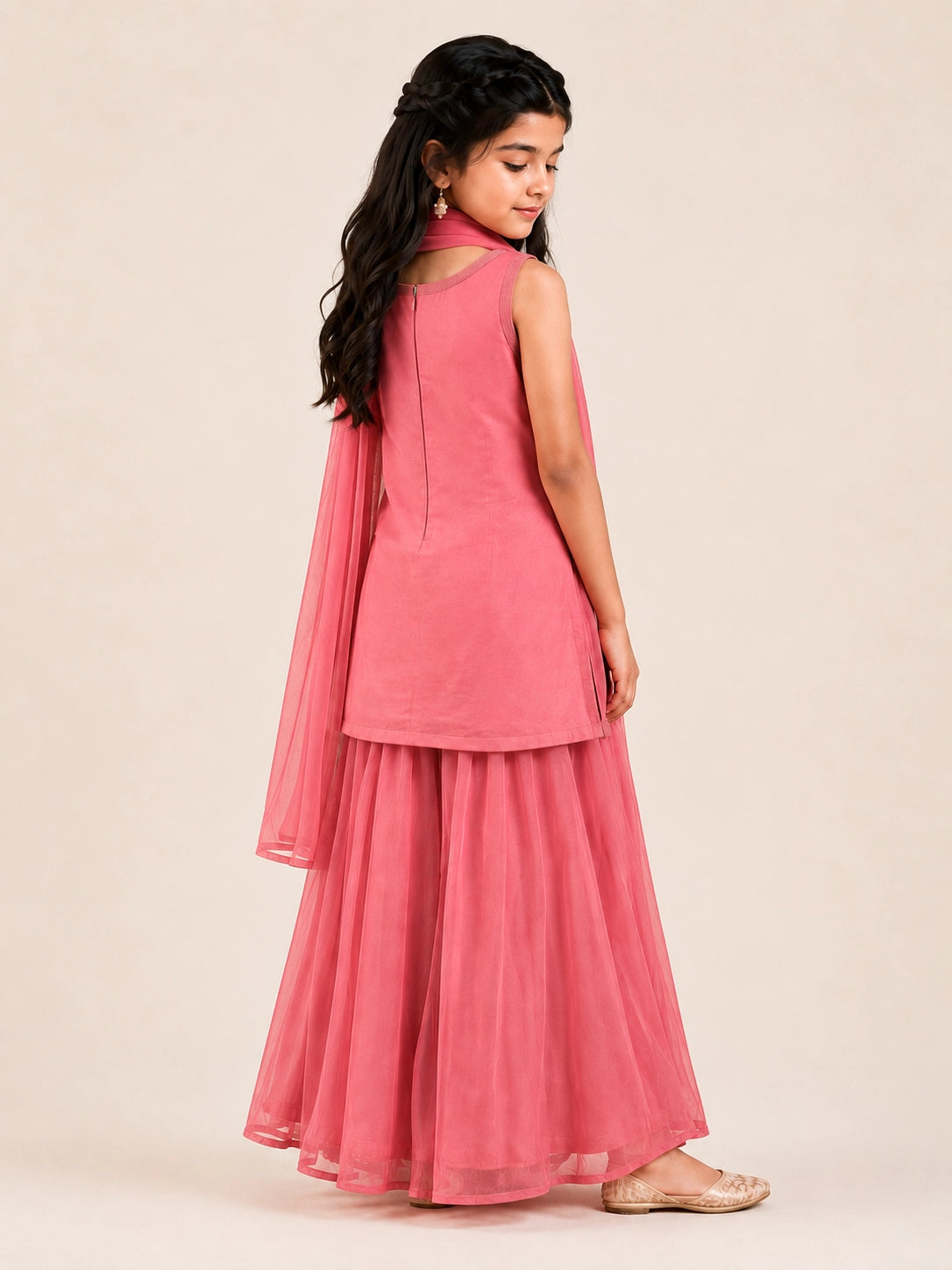 Young girl in a pink sleeveless kurta with beaded embroidery and flowy pink sharara pants.