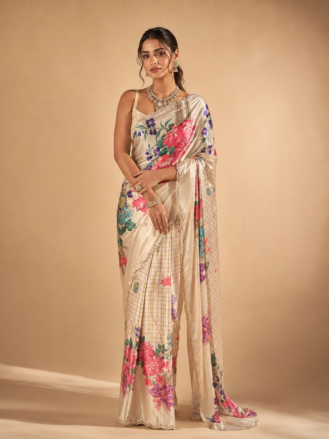 Woman in elegant cream floral saree with vibrant pink and purple flowers