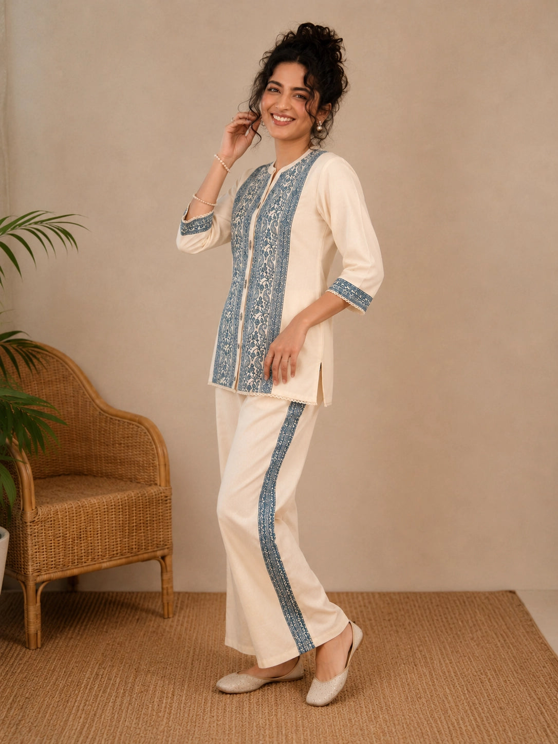 Woman wearing a cream kurta with blue paisley print, showcasing intricate embroidery and a band collar neckline.