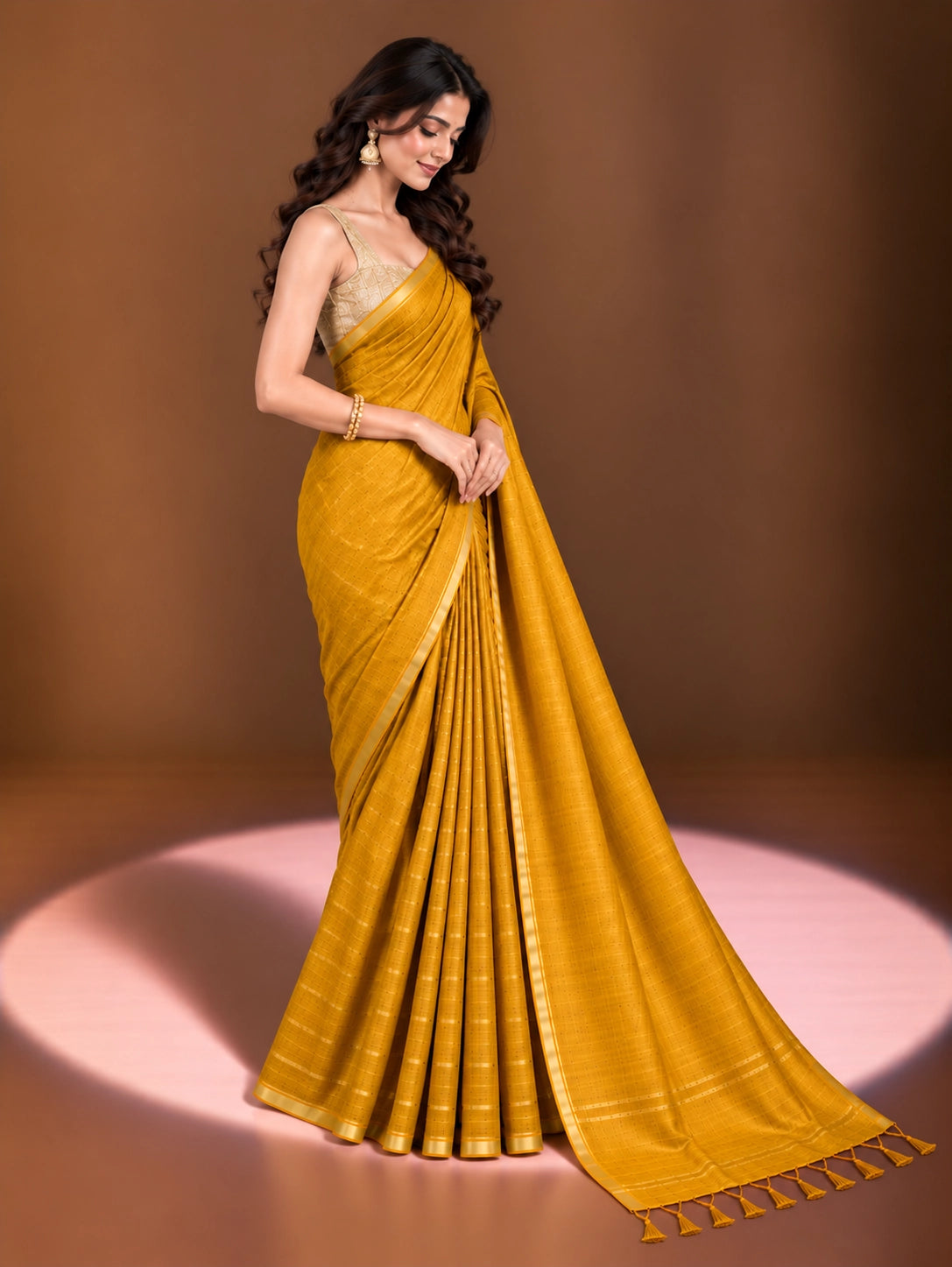 Woman modeling an elegant mustard yellow saree with a subtle woven pattern and golden border.
