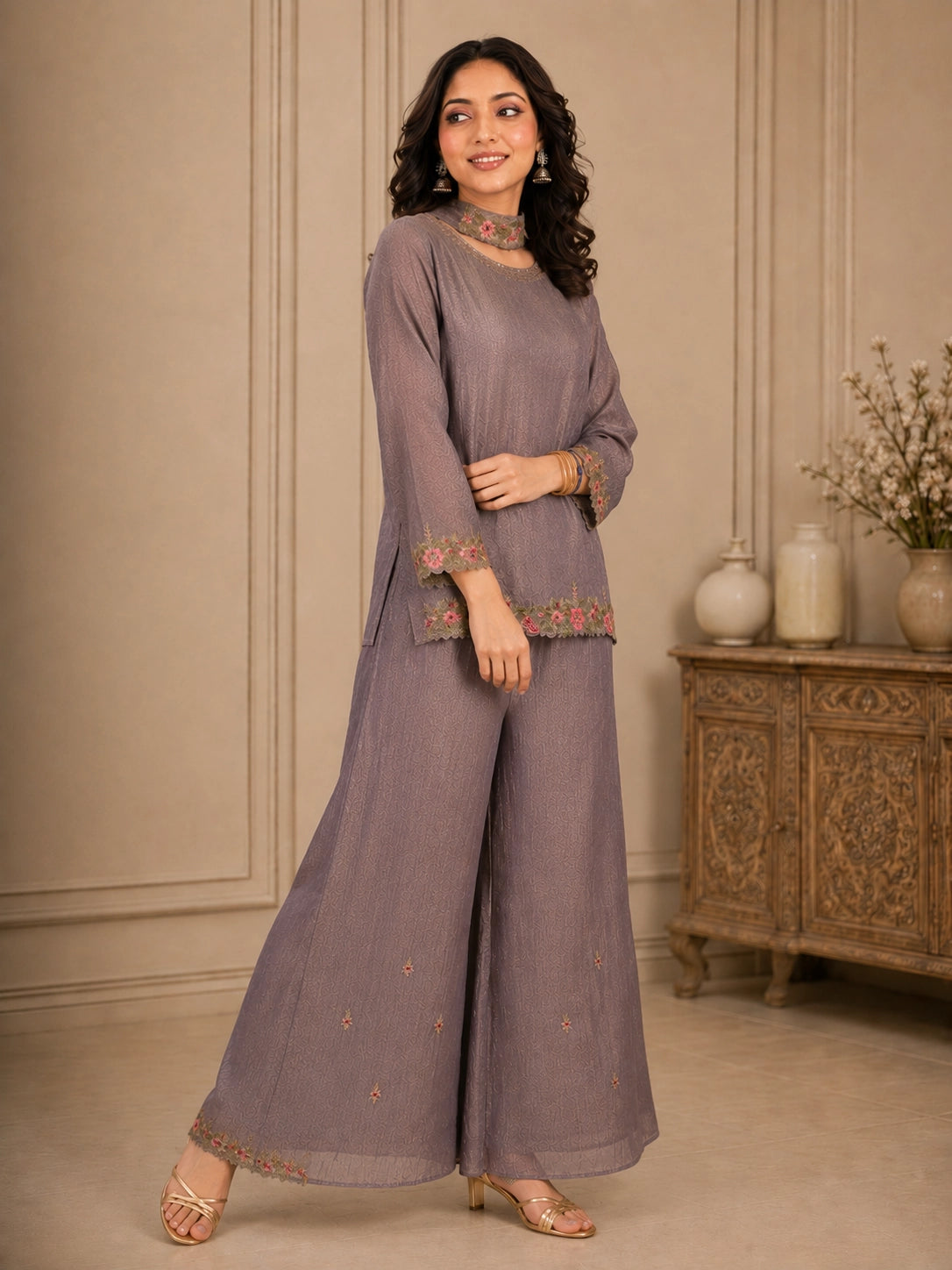 Woman wearing a pink embroidered choker neck Sharara with floral details on sleeves and hem.