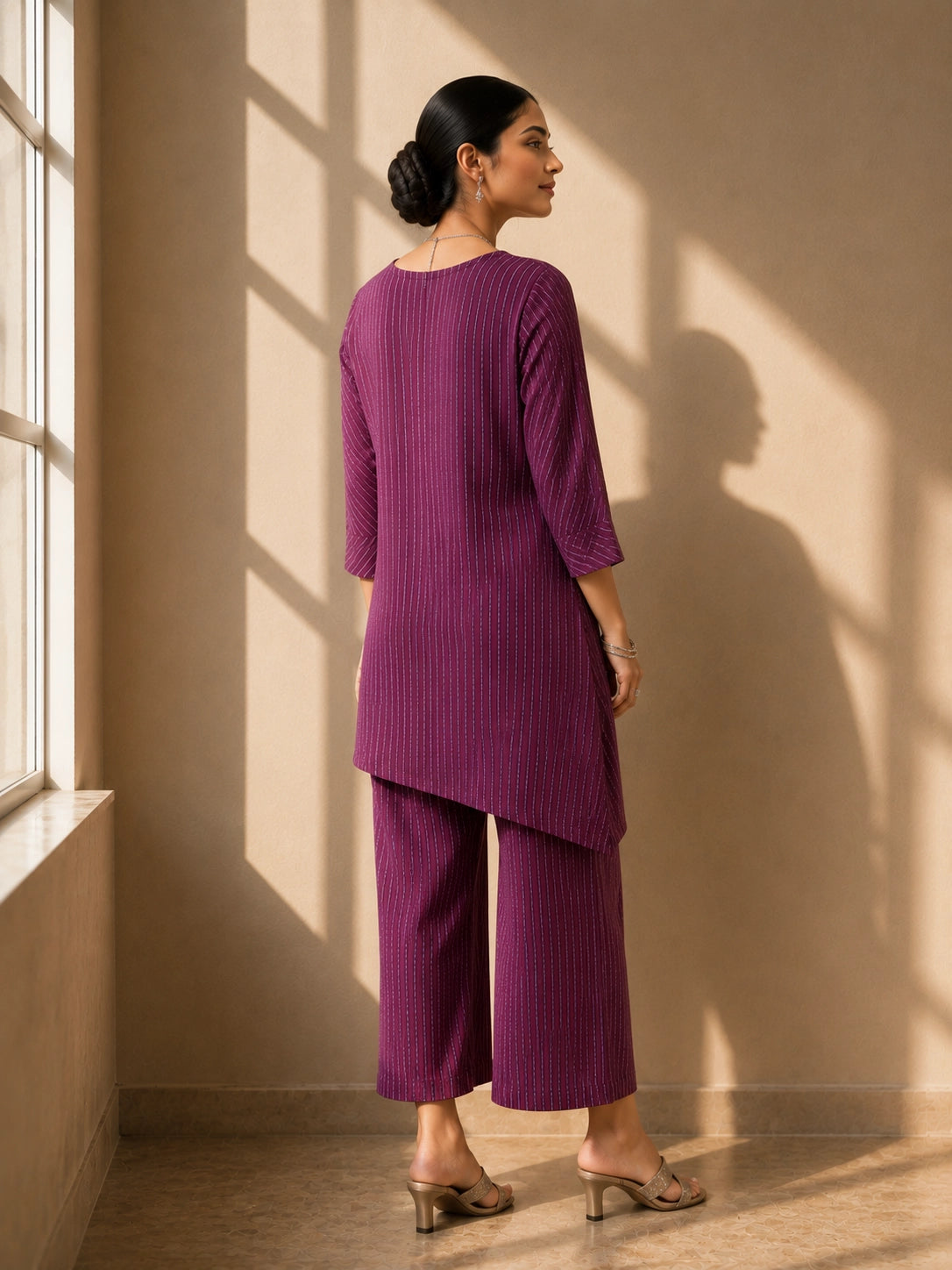 Woman wearing a purple striped V-neck top with layered hem and matching wide-leg pants.