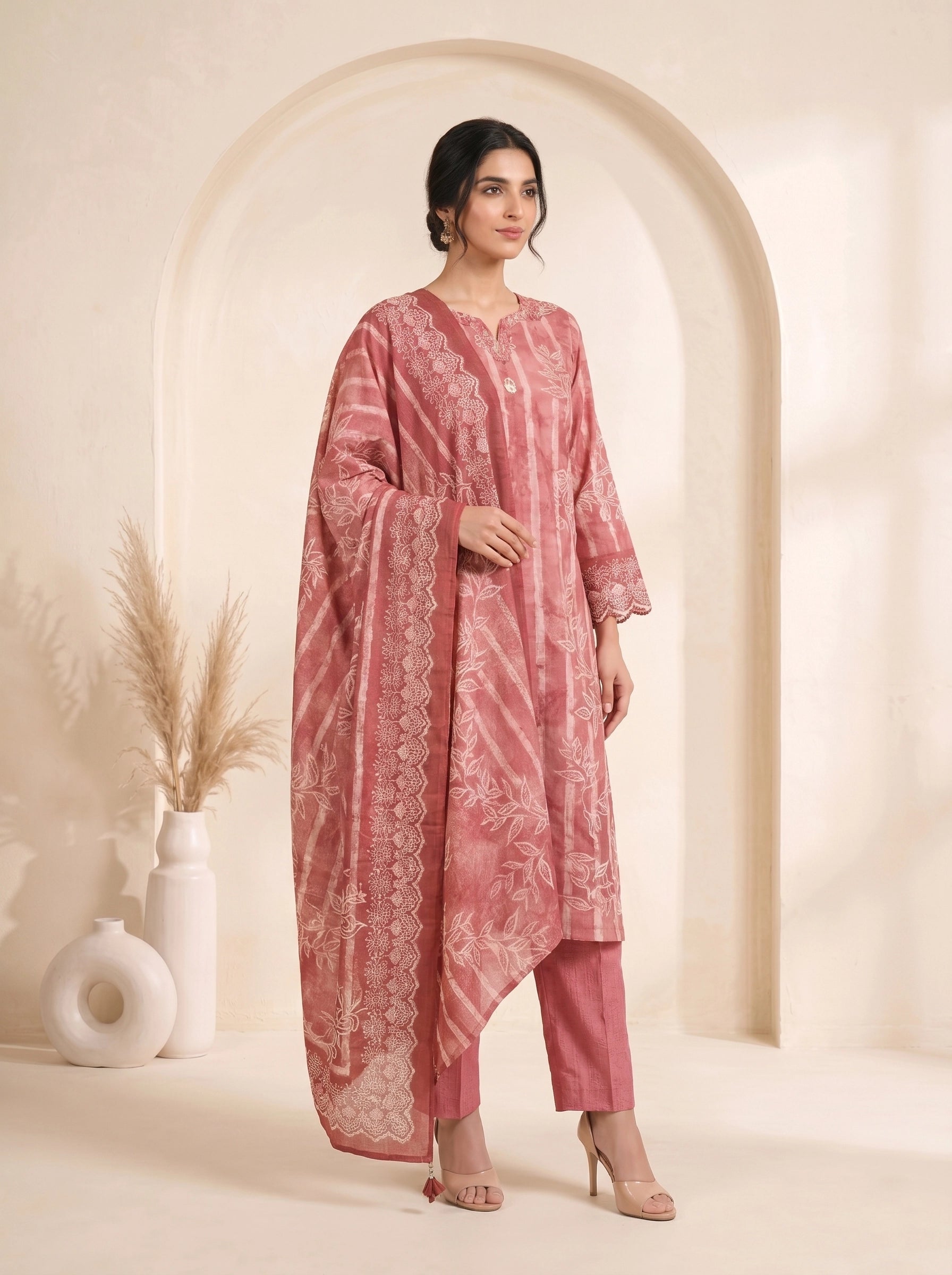 Woman wearing a rose pink printed kurti set with a dupatta, featuring leaf motifs and striped patterns.