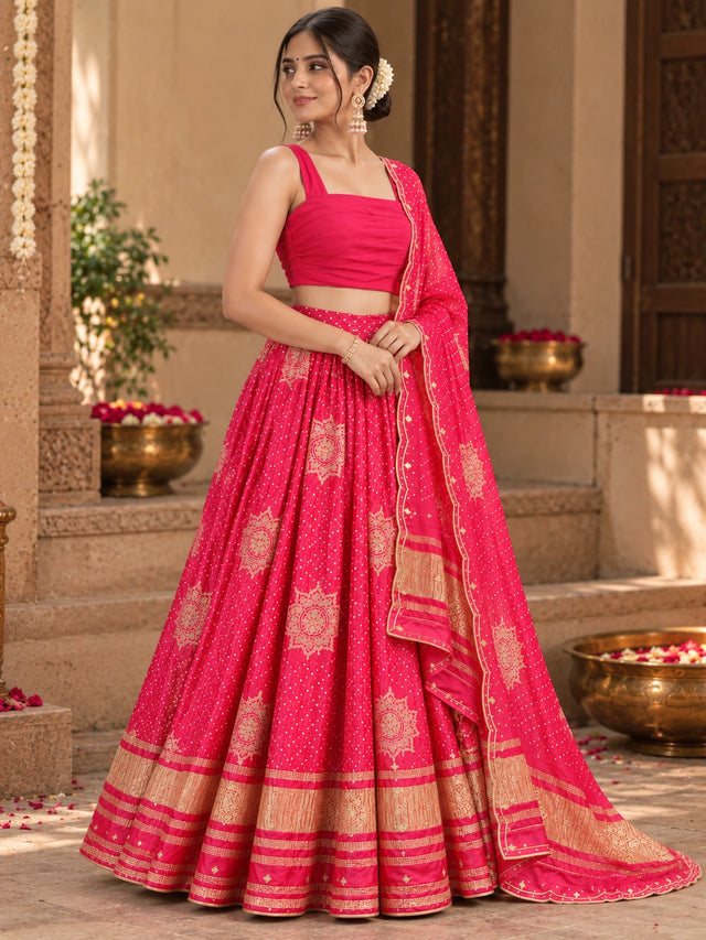 Woman wearing a vibrant RANI pink lehenga choli with gold patterns and a matching dupatta.