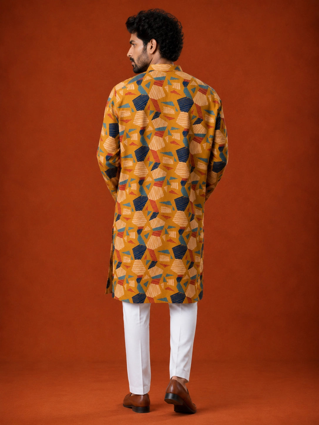 Man wearing a mustard kurta with blue, red, and white geometric print and white pajama.