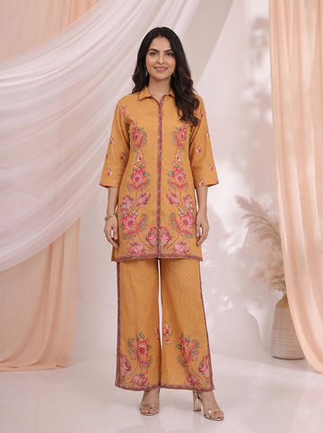 Woman wearing an ochre yellow kurta and palazzo set with a vibrant floral print.