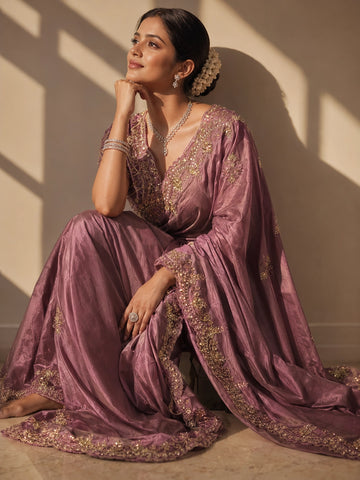 Woman in an elegant onion silk saree with intricate gold embroidery.