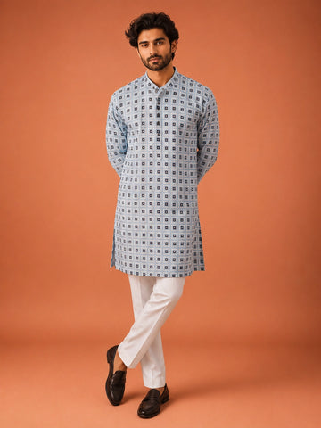 Man wearing sky blue geometric print kurta with white pajama and dark loafers.