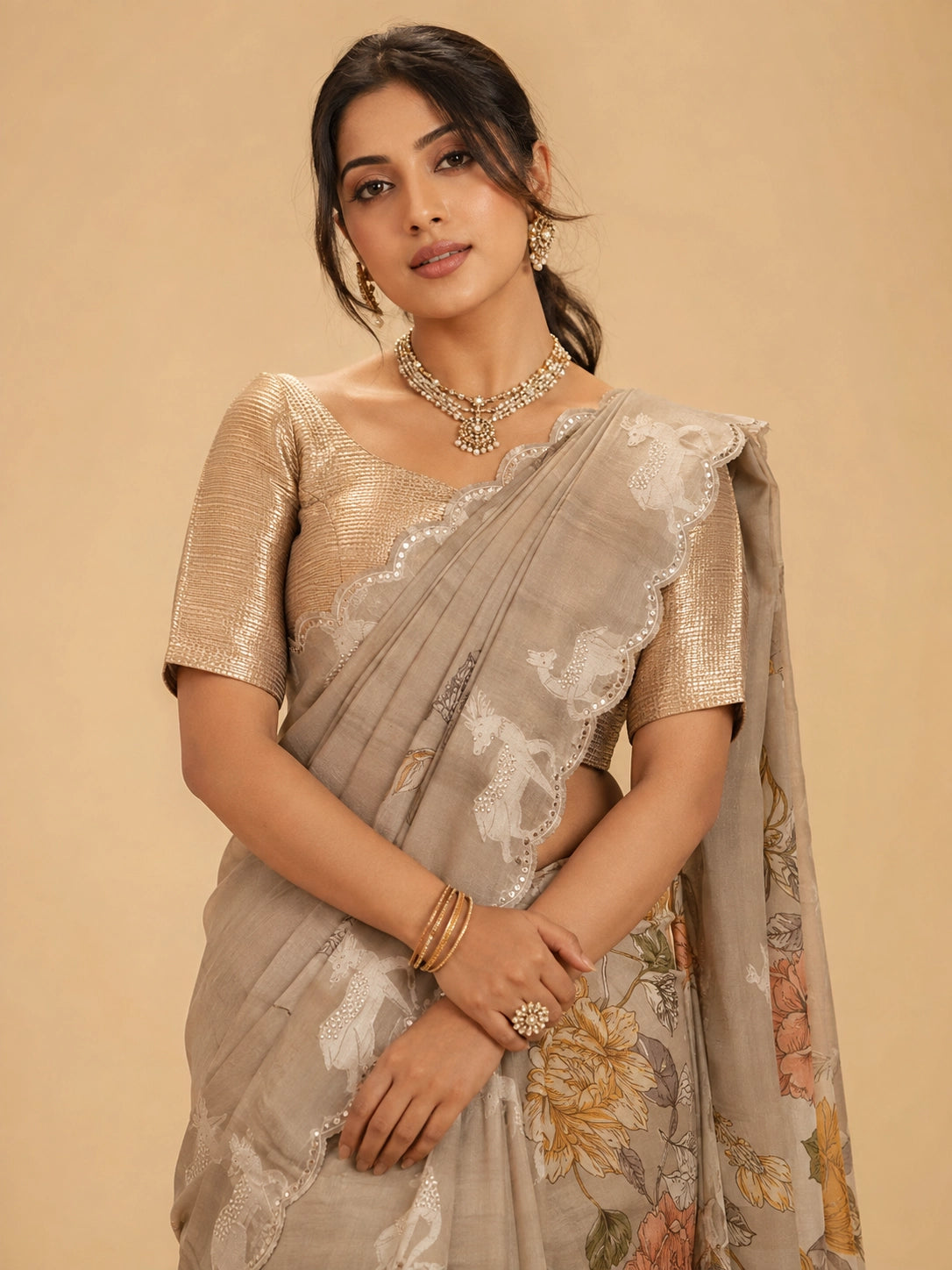 Woman wearing an elegant  peach floral saree with animal motifs and a golden blouse.