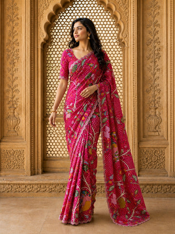 Woman in a vibrant rani pink floral saree with intricate patterns and scalloped border.