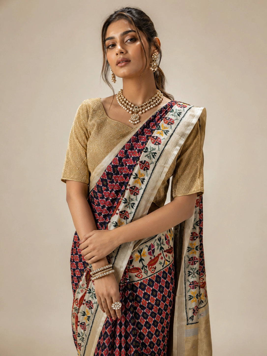 Woman wearing a purple ikat saree with a golden blouse and traditional jewelry.