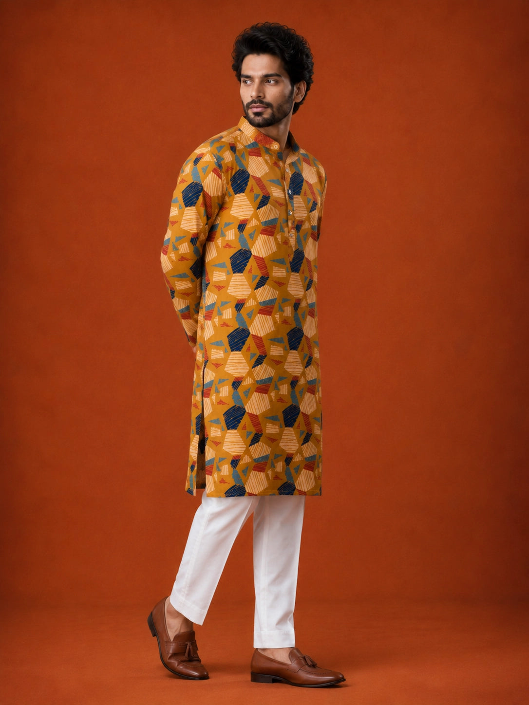 Man wearing a mustard kurta with blue, red, and white geometric print and white pajama.