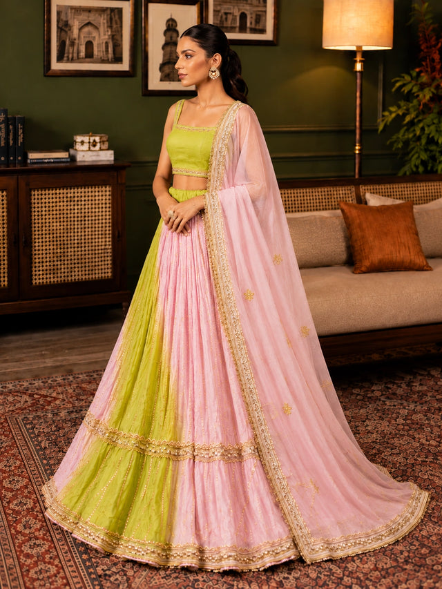 Elegant woman wearing a pink and green  lehenga choli with gold embroidery.