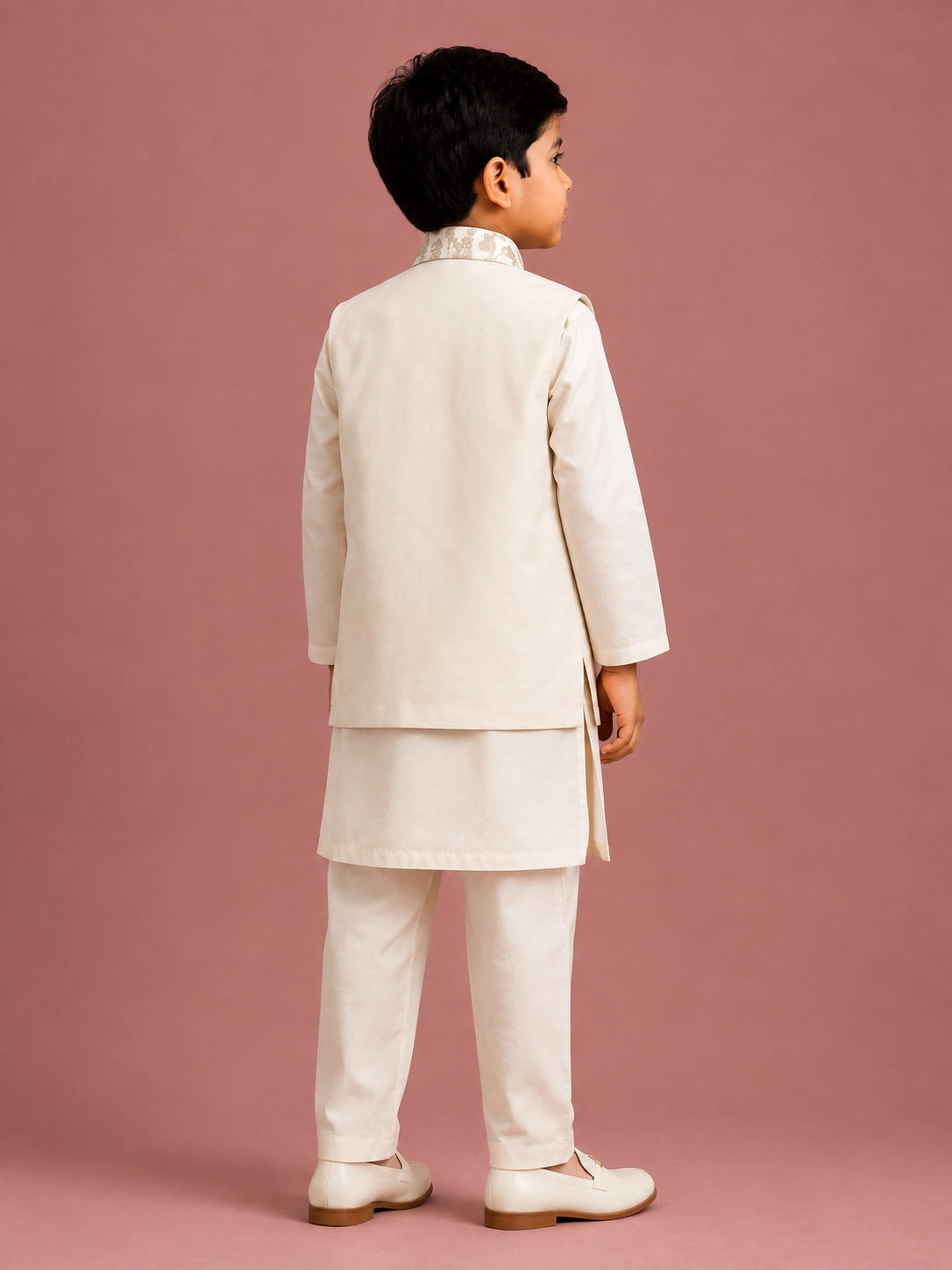 Young boy wearing an off-white embroidered bandhgala waistcoat over a kurta pajama.