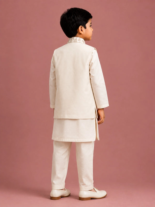 Young boy wearing an off-white embroidered bandhgala waistcoat over a kurta pajama.