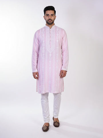 Man wearing a pink chikankari kurta with white churidar pants and brown embellished juttis.