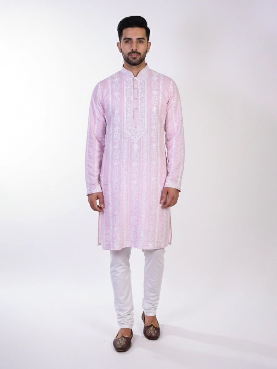 Man wearing a pink chikankari kurta with white churidar pants and brown embellished juttis.