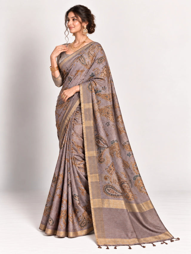 Woman in an elegant lavender grey saree with gold border and intricate paisley patterns.