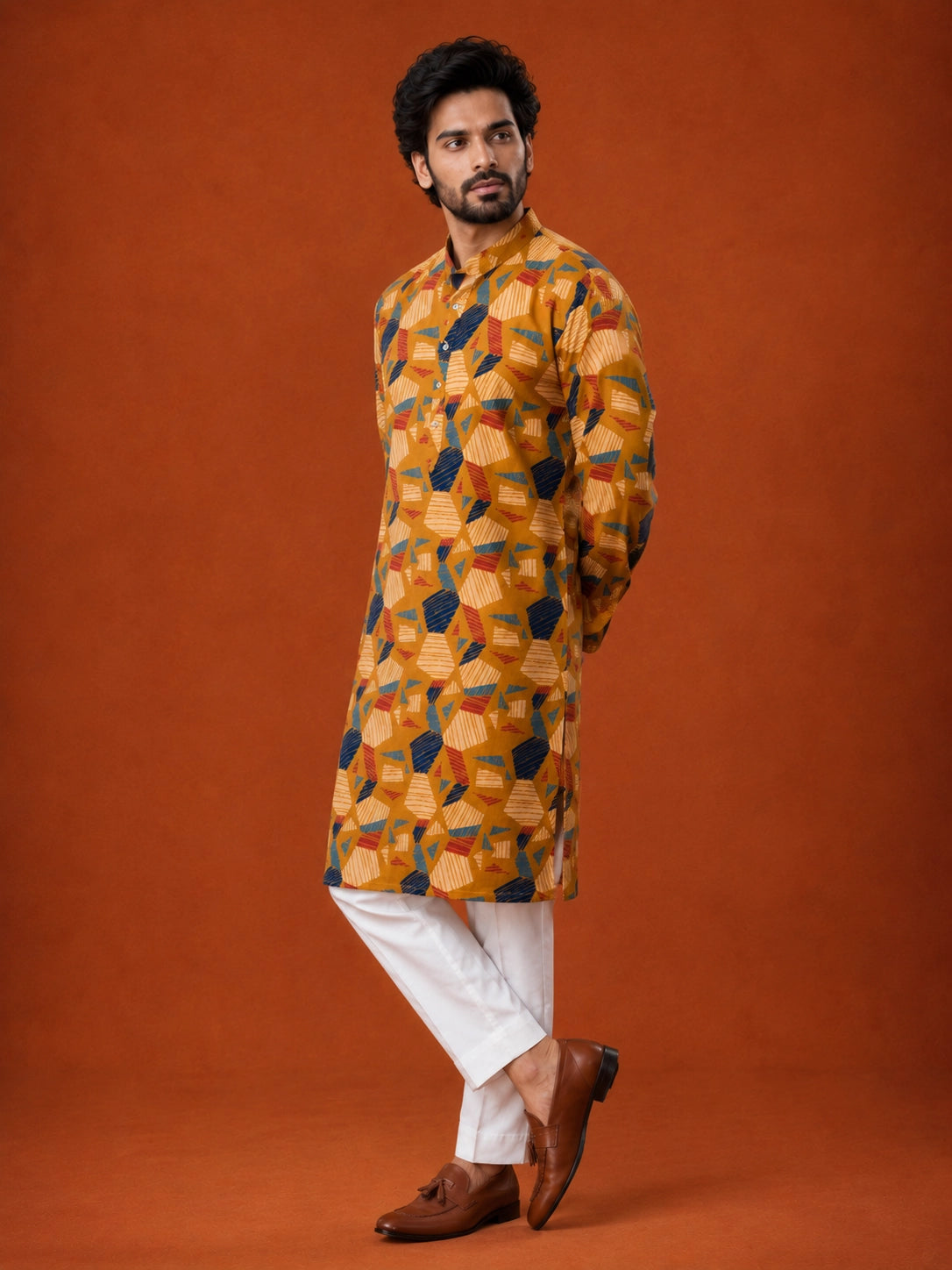 Man wearing a mustard kurta with blue, red, and white geometric print and white pajama.
