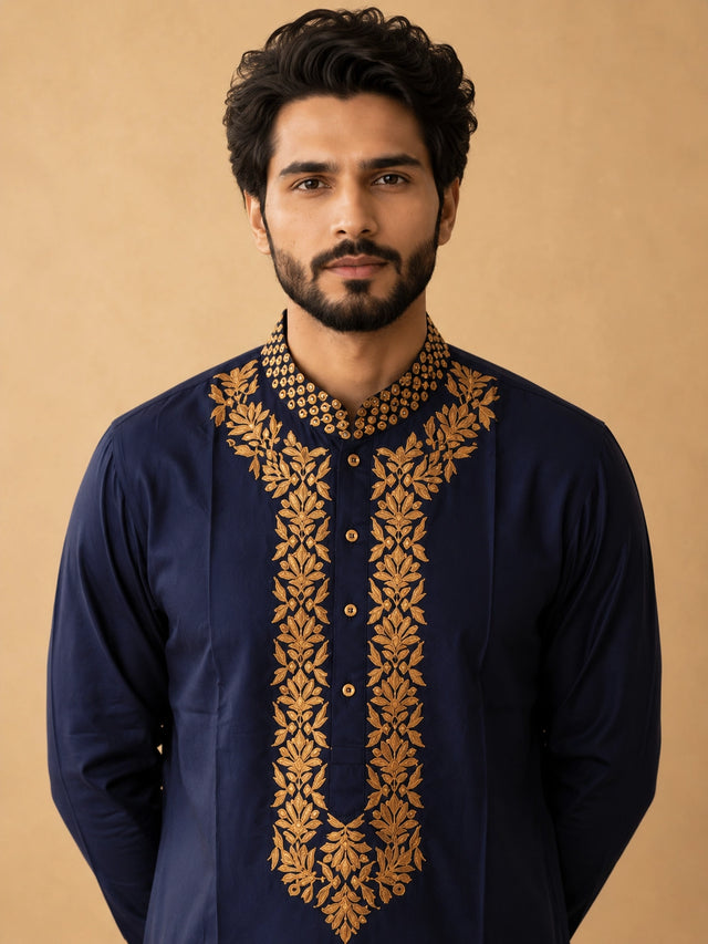 Man wearing a navy blue kurta pajama with intricate gold embroidery and elephant motifs.