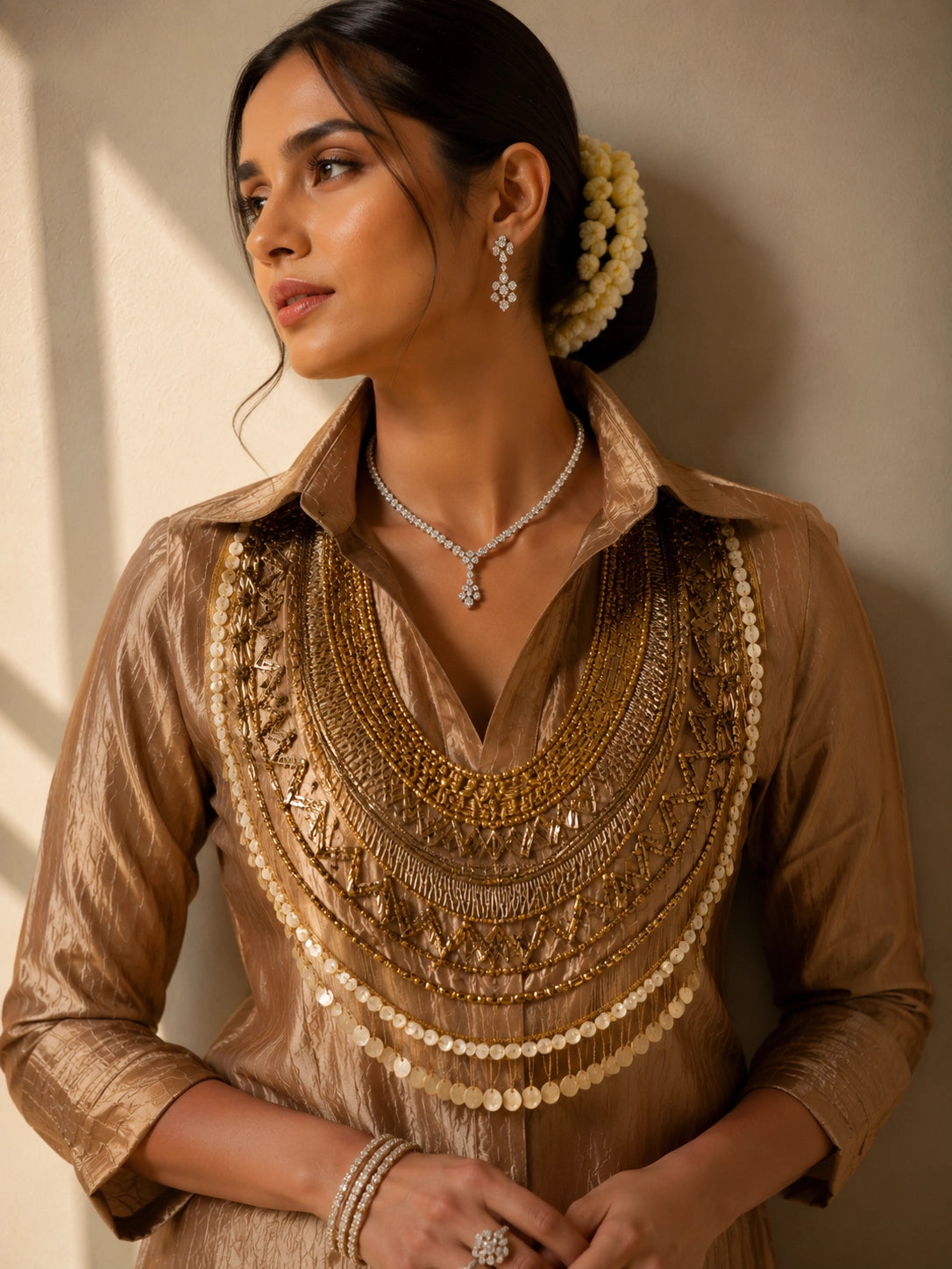 Woman wearing a shimmering brown kurti set with a heavily embroidered gold neckline.