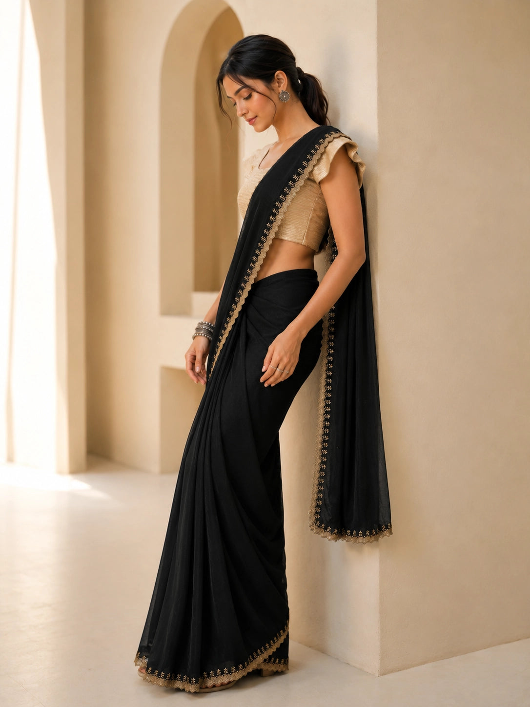 Woman in elegant black  saree with gold blouse and embroidered border.