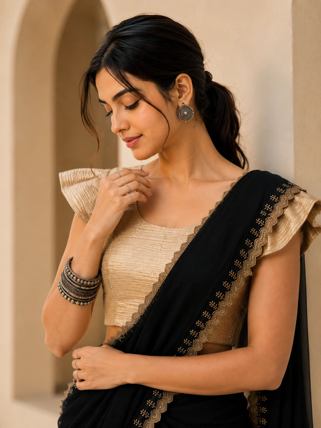 Woman in elegant black  saree with gold blouse and embroidered border.