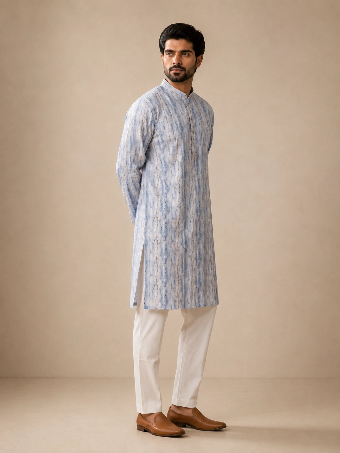Man in a dust blue printed kurta, white pajama, and brown loafers.