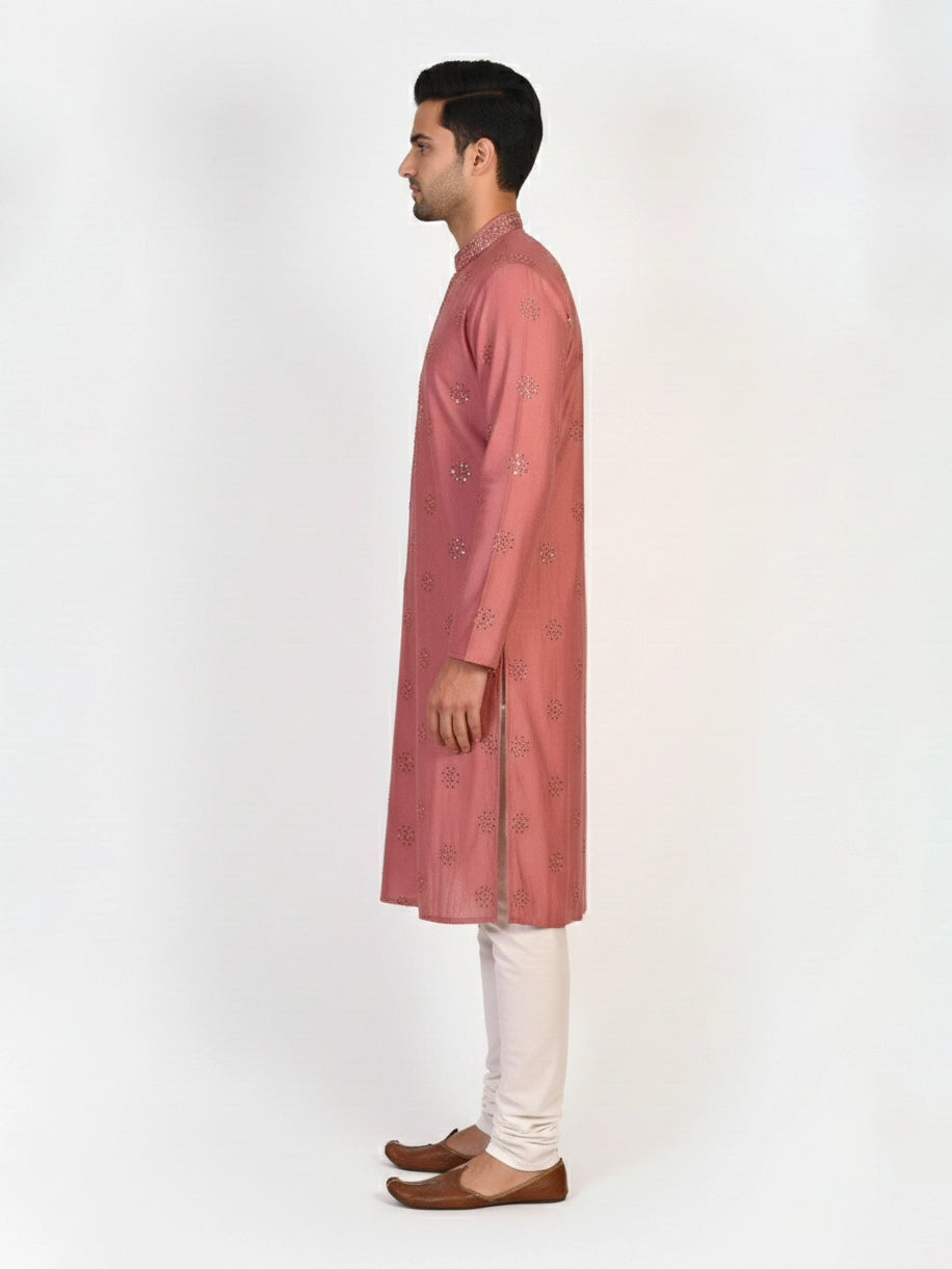Man wearing a rose embroidered Kurta Pajama with white pants and brown jutti shoes.
