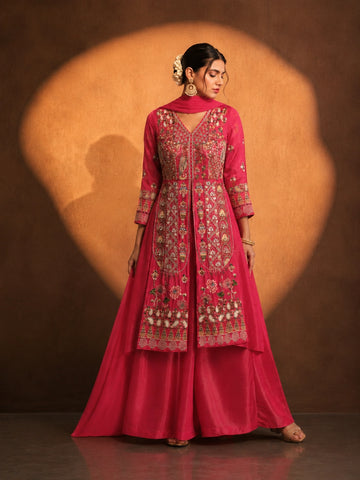 Woman in a vibrant rani pink embroidered kurti set with a flowing silhouette.